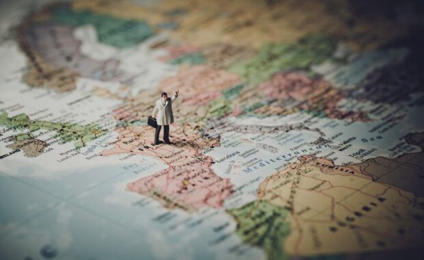 Figura en miniatura de un señor con un maletín sobre un mapa de Europa