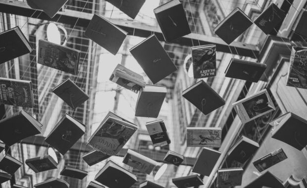 Libros colgando de cuerdas en el techo - foto en blando y negro