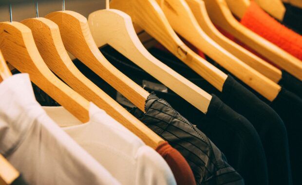 Camisetas y chaquetas colgadas de perchas y ordenadas en una tienda