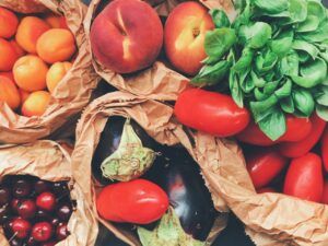 Frutas y verduras frescas dentro de bolsas de papel sobre una mesa