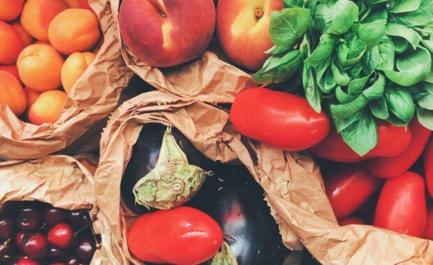 Frutas y verduras frescas dentro de bolsas de papel sobre una mesa