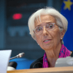 Mujer mayor de pelo claro y gafas con pañuelo rosa al cuello habla a un micrófono en el Parlamento Europeo
