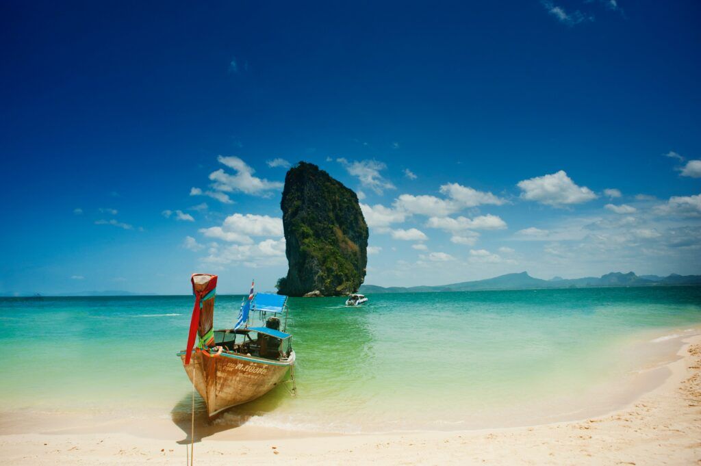 Un barco tradicional tailandés amarrado en una playa de arena blanca y aguas turquesas al sur de Tailandia.