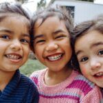 Tres niñas pequeñas sonríen a la cámara