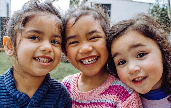 Tres niñas pequeñas sonríen a la cámara