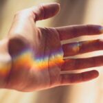 Mano tendida en son de paz con un reflejo de arcoiris en ella