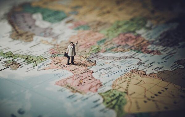 Figura en miniatura de un señor con un maletín sobre un mapa de Europa