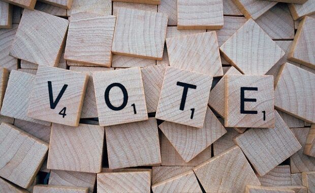 fichas de madera con letras en color negro que forman la palabra "VOTE"