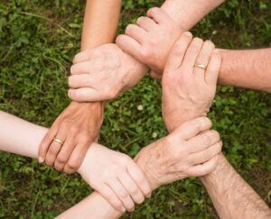 cinco manos unidas sobre un fondo de césped