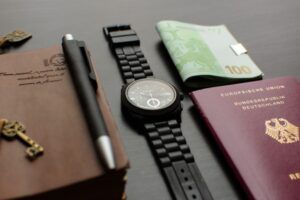 Pasaporte de la República de Alemania sobre una mesa junto a otros objetos personales como un reloj negro, un bolígrafo o dinero