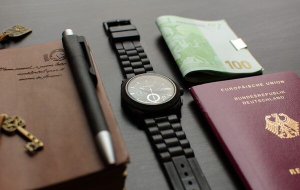 Pasaporte de la República de Alemania sobre una mesa junto a otros objetos personales como un reloj negro, un bolígrafo o dinero