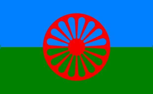 Bnadera compuesta de una franja verde abajo y una azul claro arriba con una rueda de carromato roja en el centro
