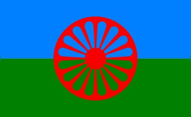 Bnadera compuesta de una franja verde abajo y una azul claro arriba con una rueda de carromato roja en el centro