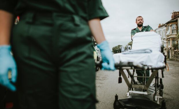 Equipos de emergencias van a atender a alguien empujando una camilla y llevando guantes de látex