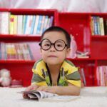 niño con gafas lee en una biblioteca