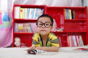 niño con gafas lee en una biblioteca