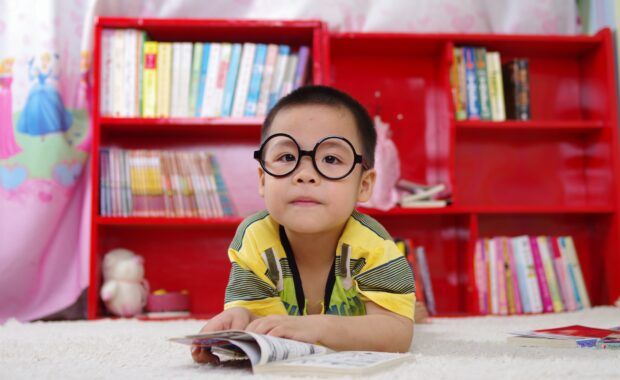 niño con gafas lee en una biblioteca