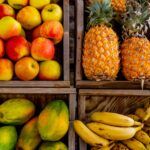 Cuatros cestas llenas de fruta: manzana, papaya, piña y plátano
