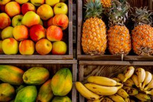 Cuatros cestas llenas de fruta: manzana, papaya, piña y plátano