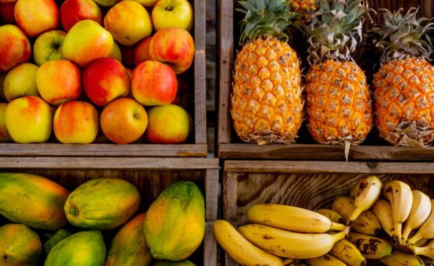 Cuatros cestas llenas de fruta: manzana, papaya, piña y plátano