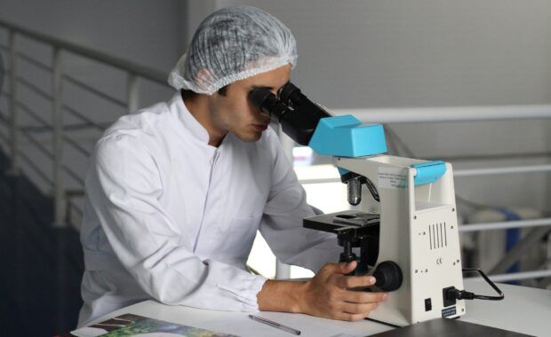 investigador mirando a través de un microscopio