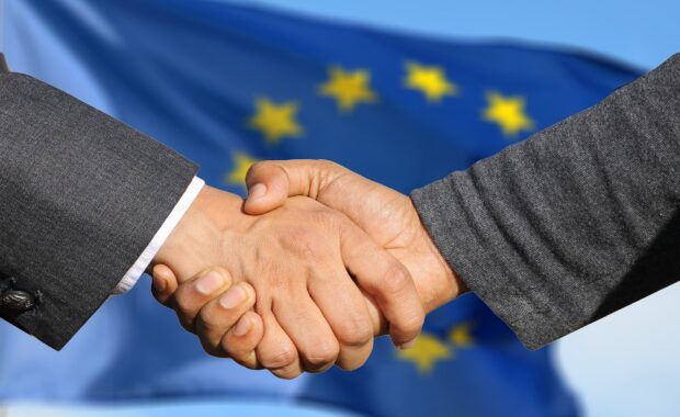 manos acuerdo con la bandera europea detrás