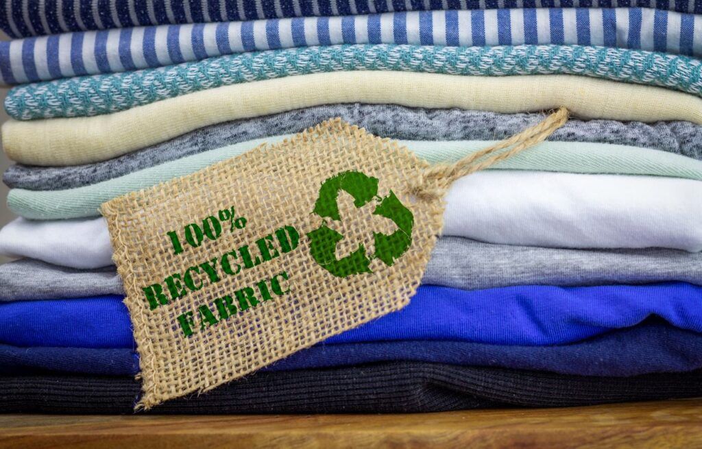 Icono de ropa reciclada en etiqueta de tela con texto 100% reciclado. 