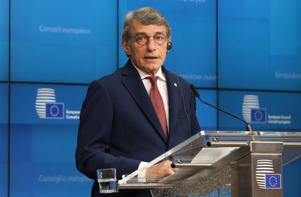 The EP President standing at a lectern and microphone speaking in a navy blue suit and red tie.