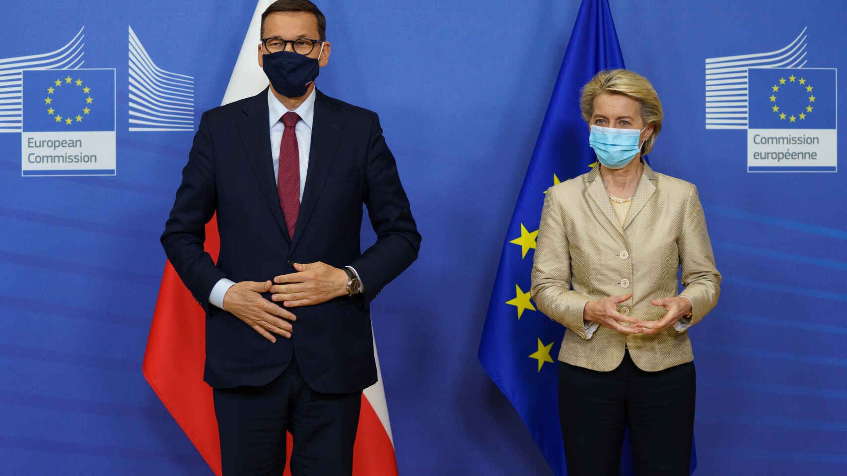 A man and a woman, standing, pose with the flag of the European Union and Poland behind them.
