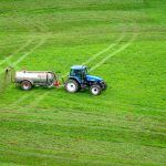 tractor con fertilizante en campo verde