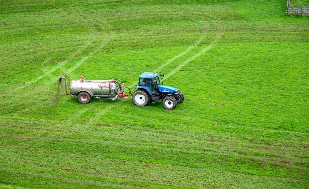 tractor con fertilizante en campo verde