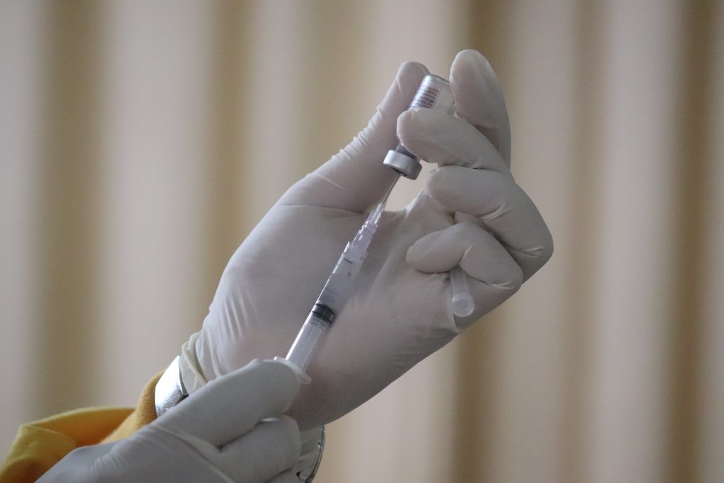 manos sujetan una jeringuilla y una dosis de una vacuna