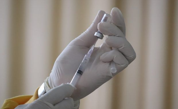 manos sujetan una jeringuilla y una dosis de una vacuna