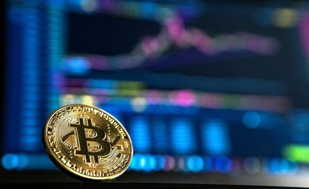 moneda de bitcoin dealnte de una pantalla de ordenador