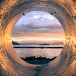 Vista del mar desde el interior de una gran tubería industrial