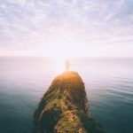 Una persona mira el horizonte marino desde lo alto de un peñón