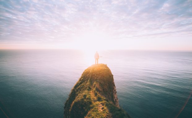 Una persona mira el horizonte marino desde lo alto de un peñón