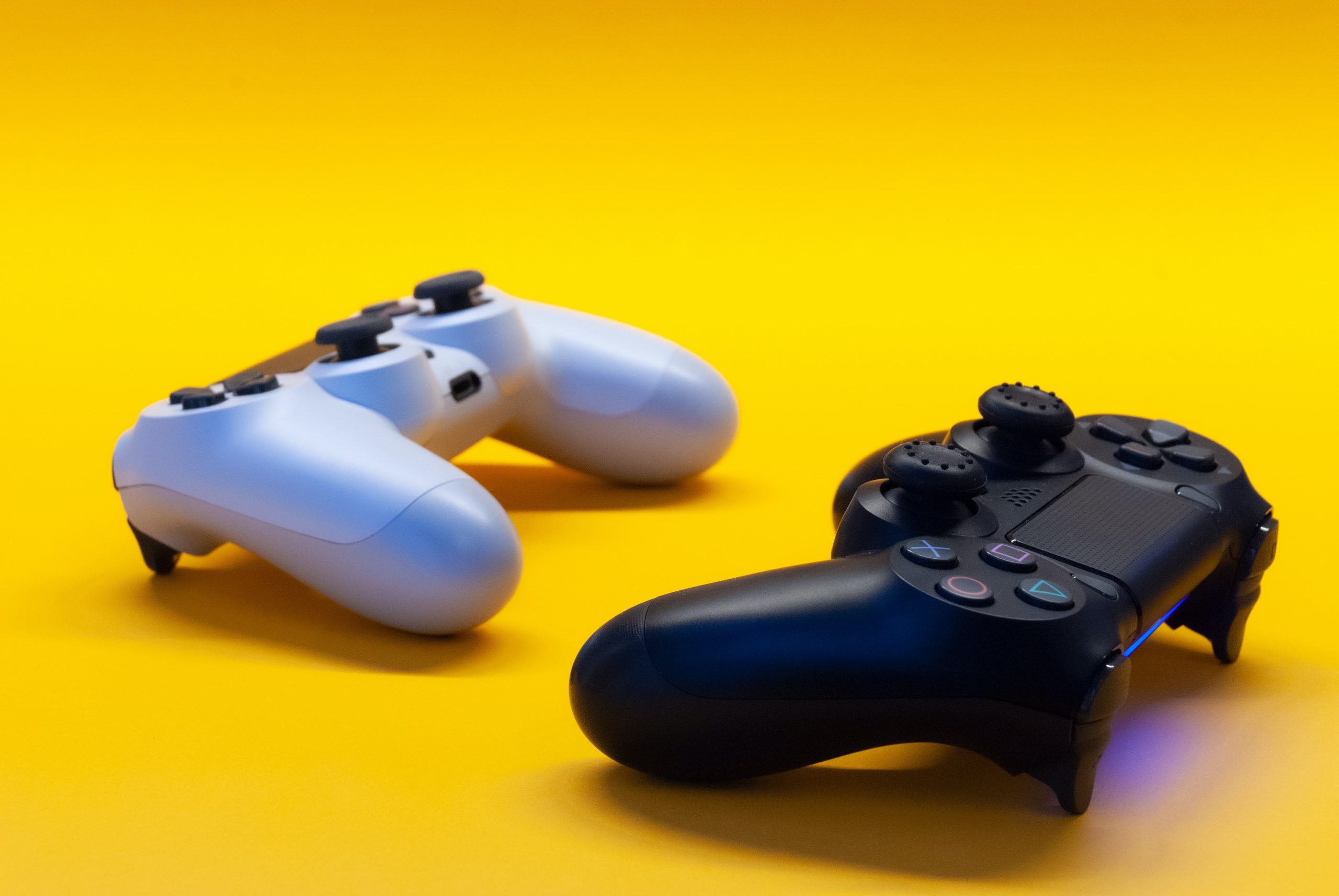 Dos mandos de consola de videojuegos sobre un fondo plano amarillo