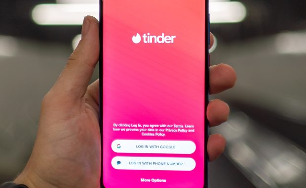 Plano detalle de una mano que sostiene un teléfono móvil con la aplicación Tinder