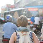 Vista trasera de una mujer con mochila que camina entre la multitud en un centro urbano