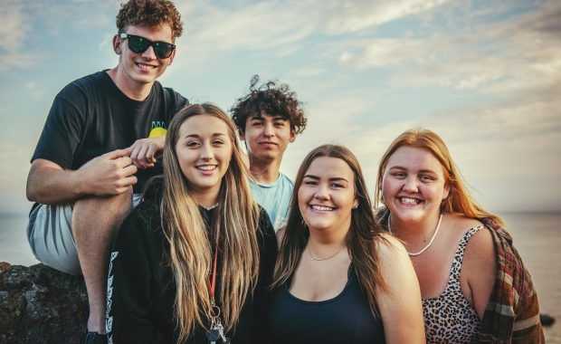 Jóvenes posan en grupo mirando a cámara sonriendo