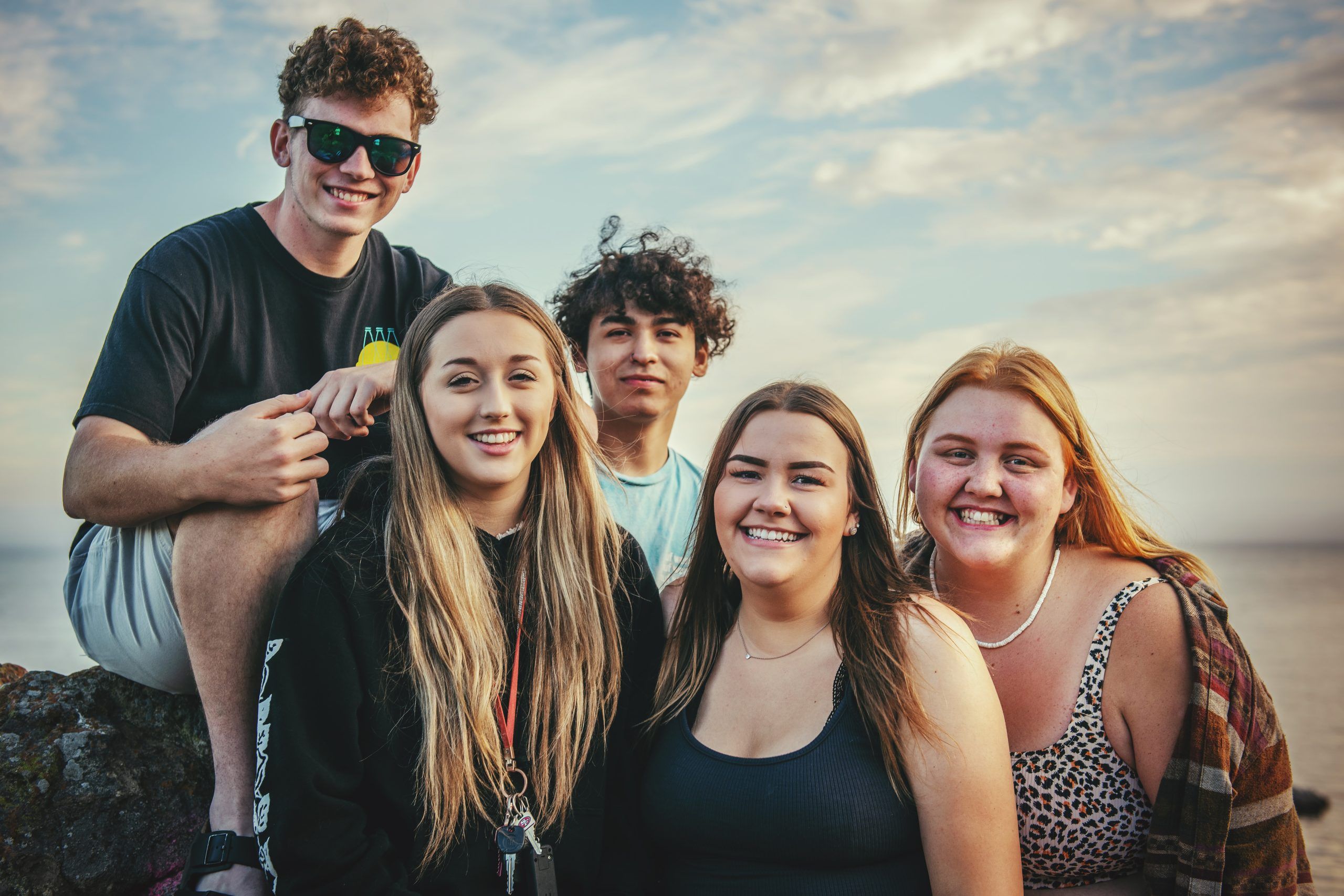 Jóvenes posan en grupo mirando a cámara sonriendo