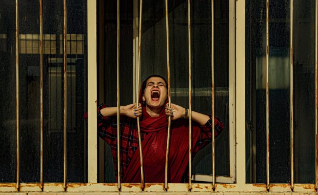 Mujer árabe grita tras los barrotes de una prisión