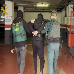 Guardia Civil de espaldas llevando a un preso esposado