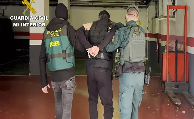 Guardia Civil de espaldas llevando a un preso esposado