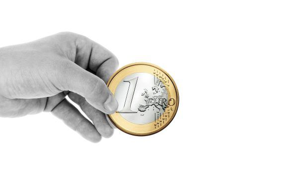 Mano en blanco y negro sujeta una moneda de un euro de gran tamaño y a color