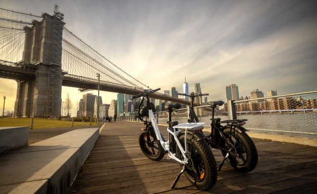 Dos bicicletas eléctricas paradas frente a un gran puente