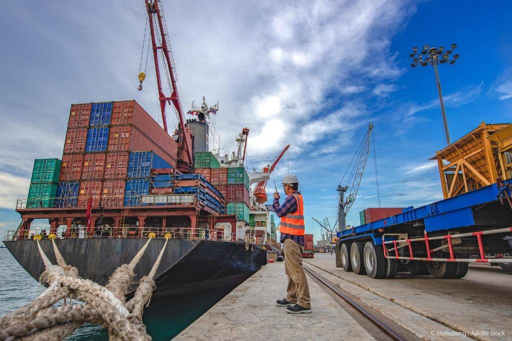 vista trabajador en un puerto y un barco de carga