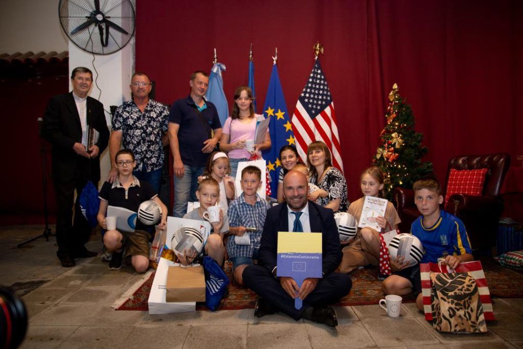 grupo de adultos y niños con regalos y banderas de Europa y EEUU