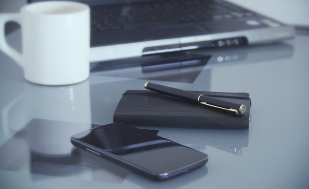 portátil sobre mesa de escritorio con taza de té y un móvil